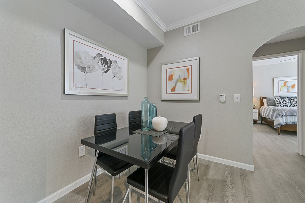 a dining area with a glass table and four black chairs