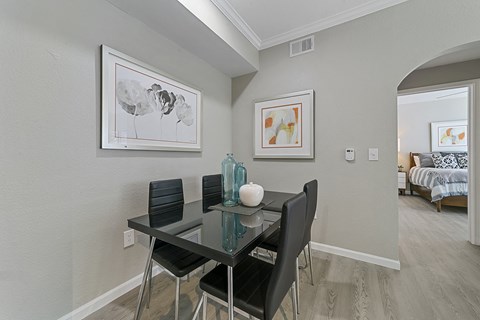 a dining area with a glass table and four black chairs