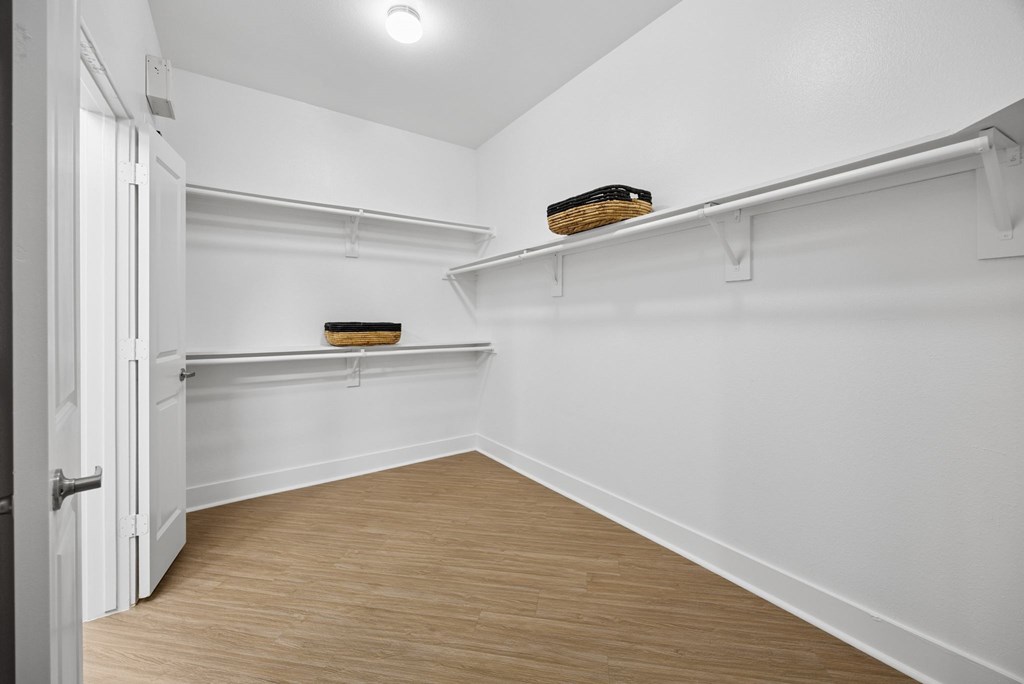 A white room with a wooden floor and a door on the left.