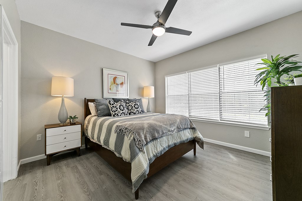 a bedroom with a large window and a ceiling fan