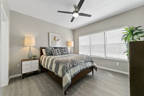 a bedroom with a large window and a ceiling fan