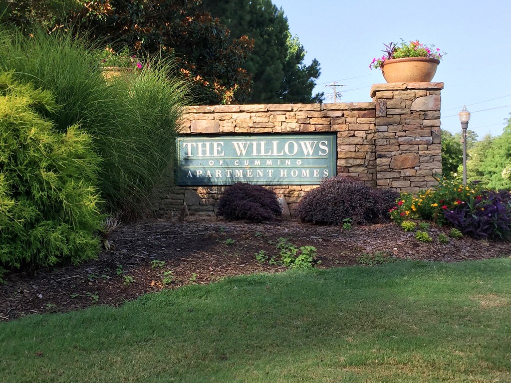a sign for the willows residential home in front of a stone wall