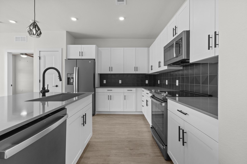 A modern kitchen with white cabinets and black countertops.