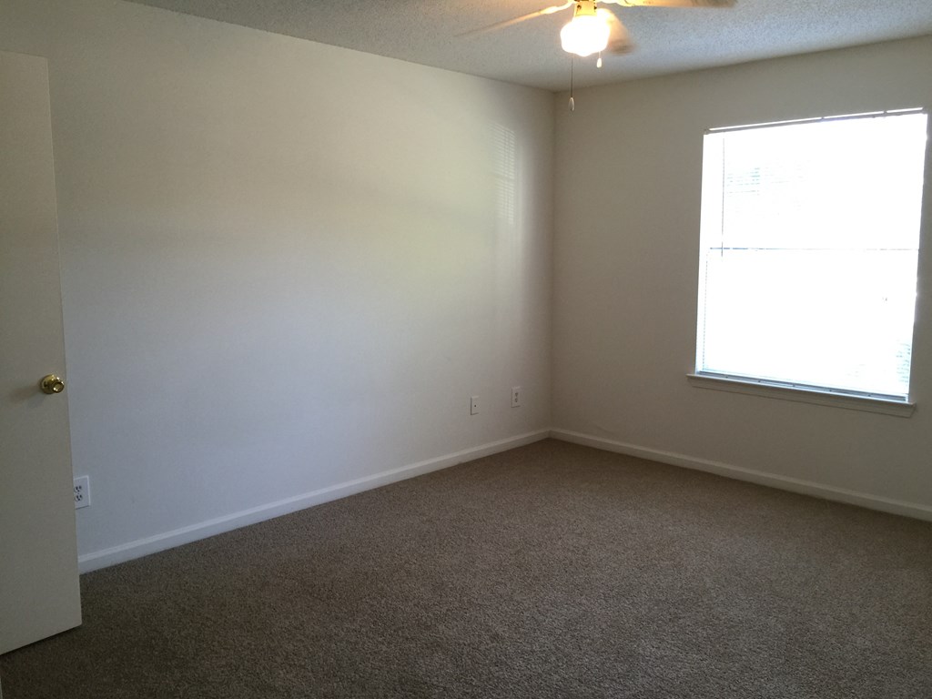an empty living room with a window and carpet