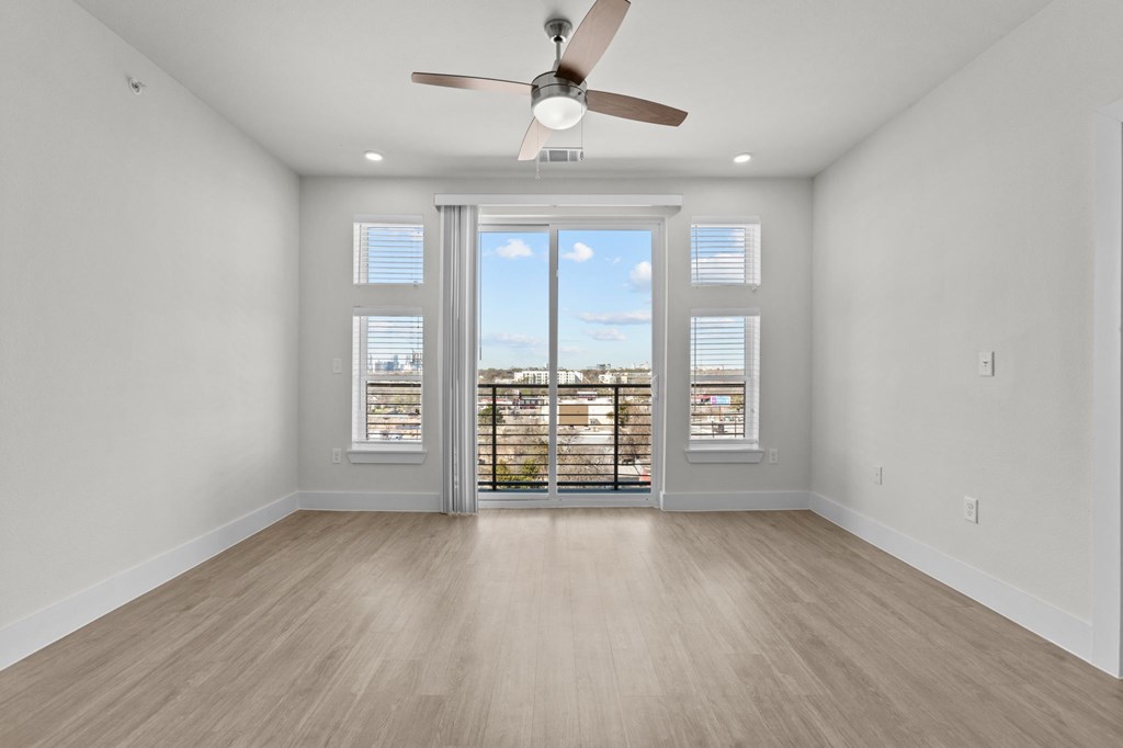 A room with a ceiling fan and sliding glass doors.