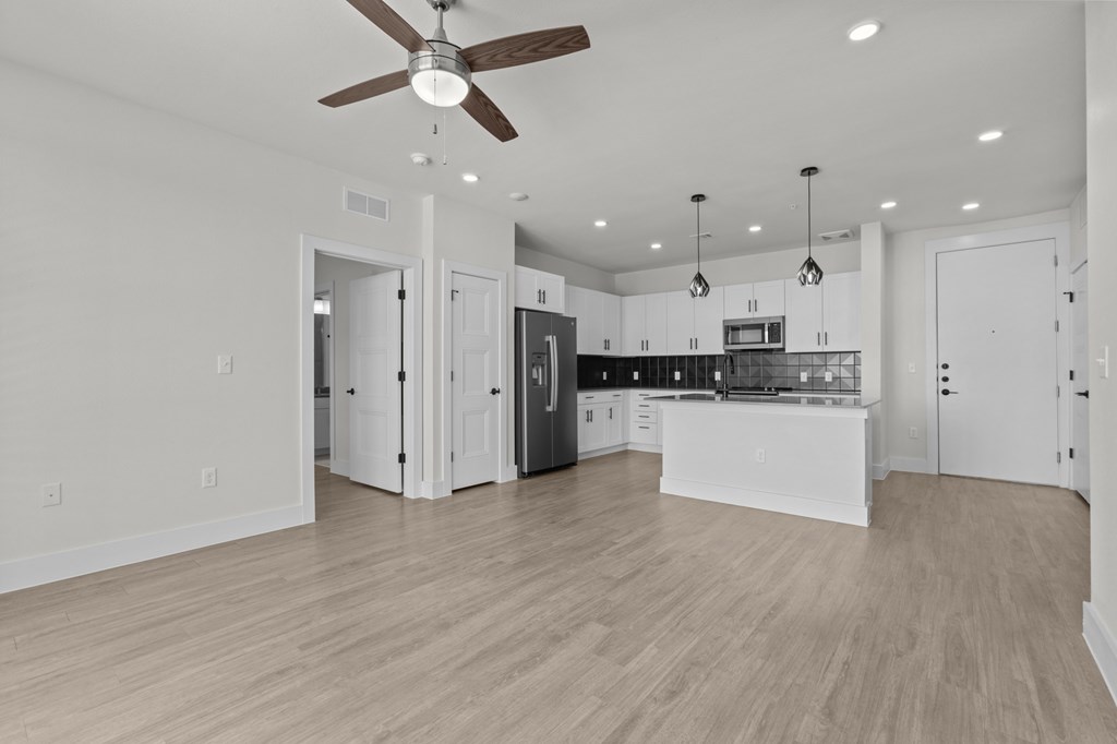 A spacious kitchen with a ceiling fan and pendant lights.