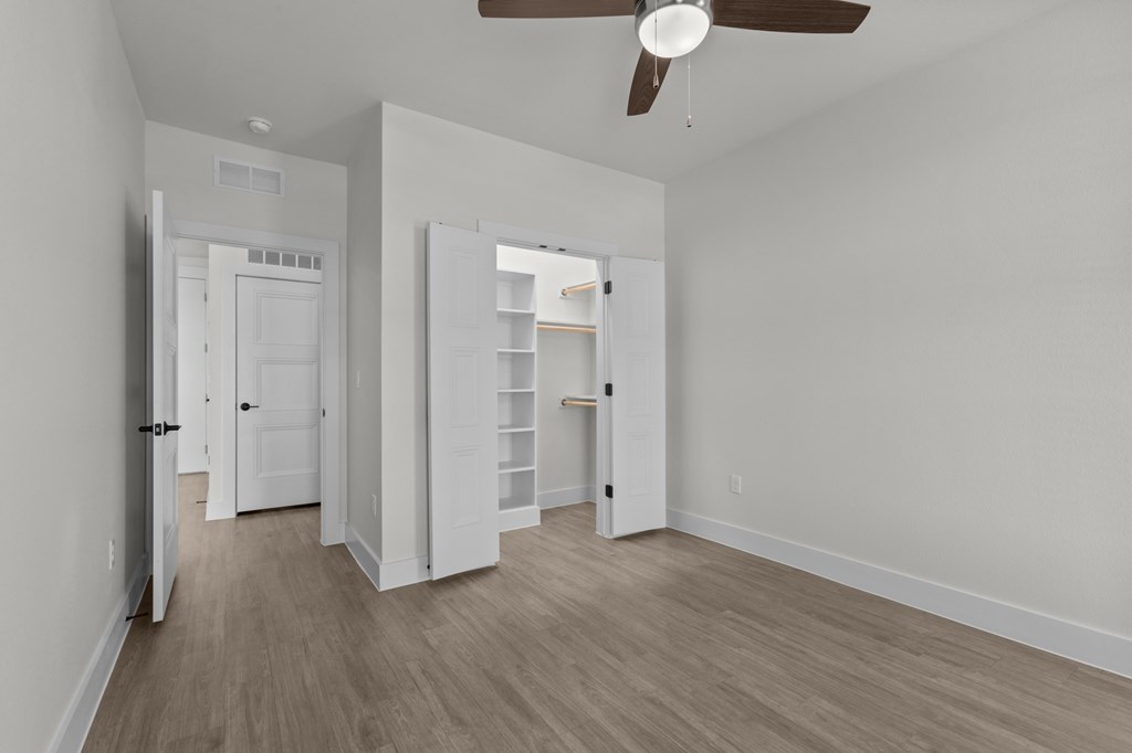 A room with a ceiling fan and light, and a doorway leading to another room.