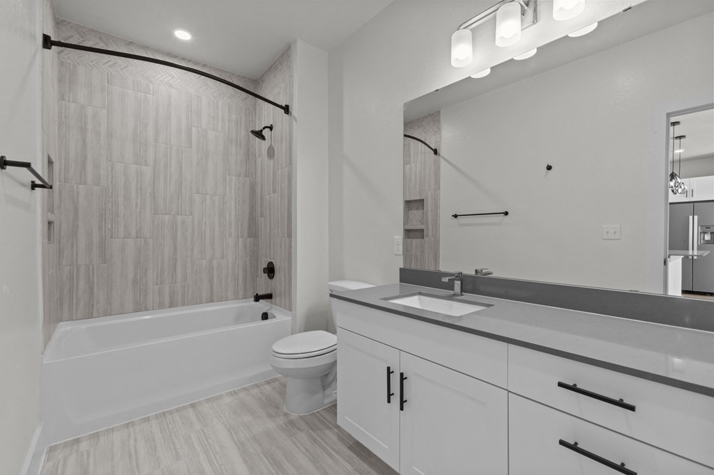 A modern bathroom with a white tub, sink, and toilet.