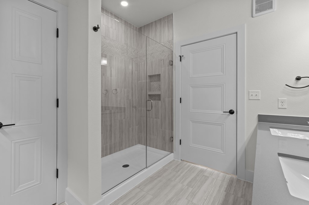 A bathroom with a walk-in shower and a white door.