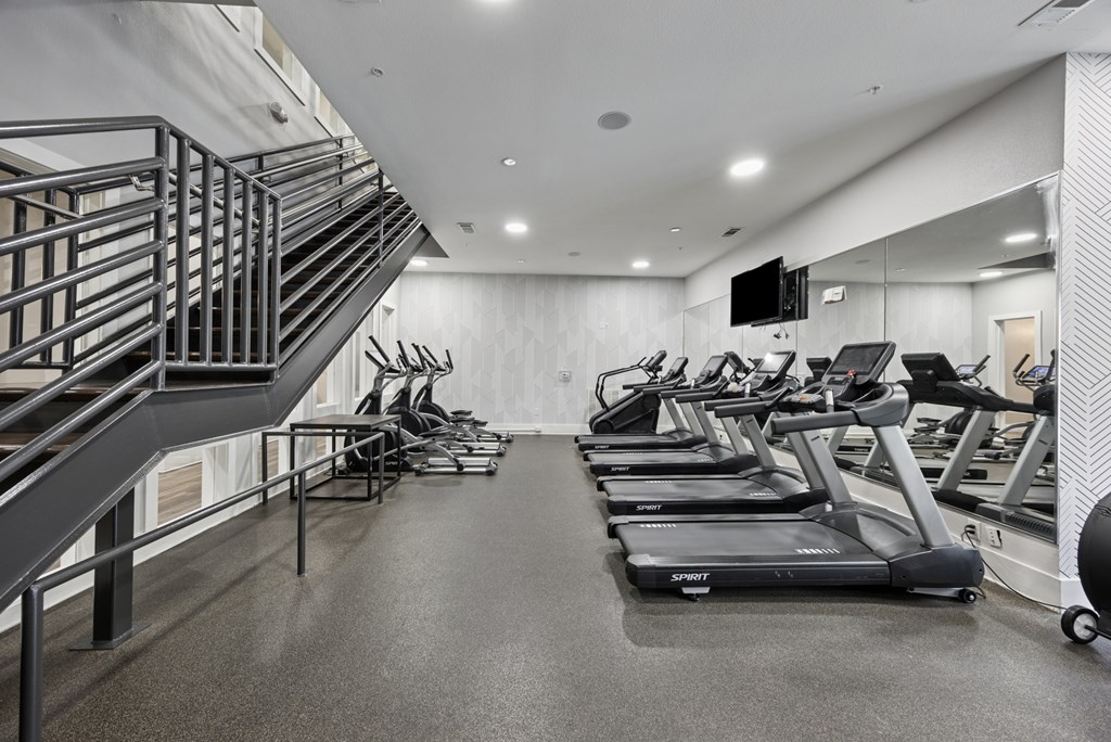 A gym with treadmilers and a staircase.