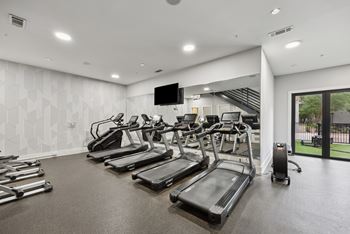 A gym with treadmills and a television.