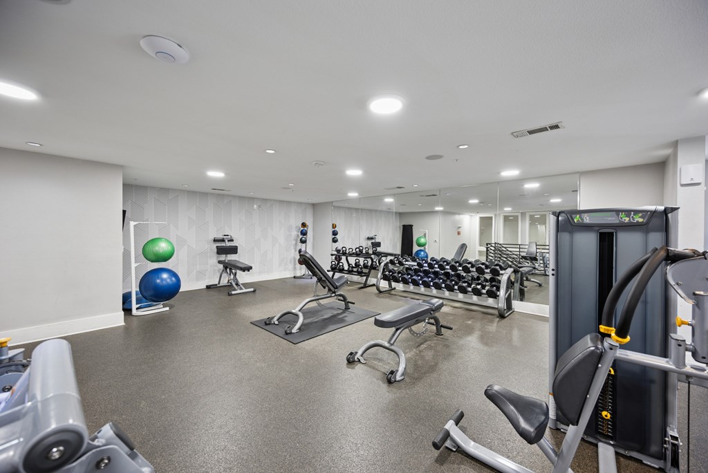 A gym with a variety of equipment including weights and exercise balls.