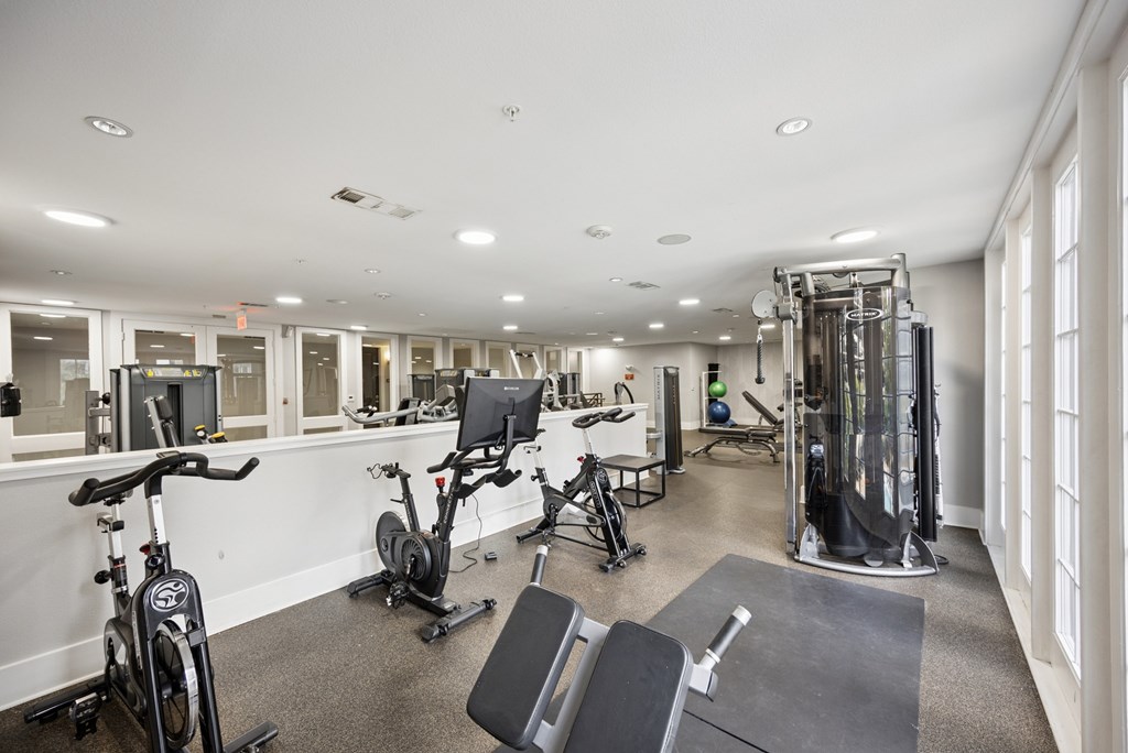 A spacious gym with a variety of equipment including treadmills, stationary bikes, and weight machines.