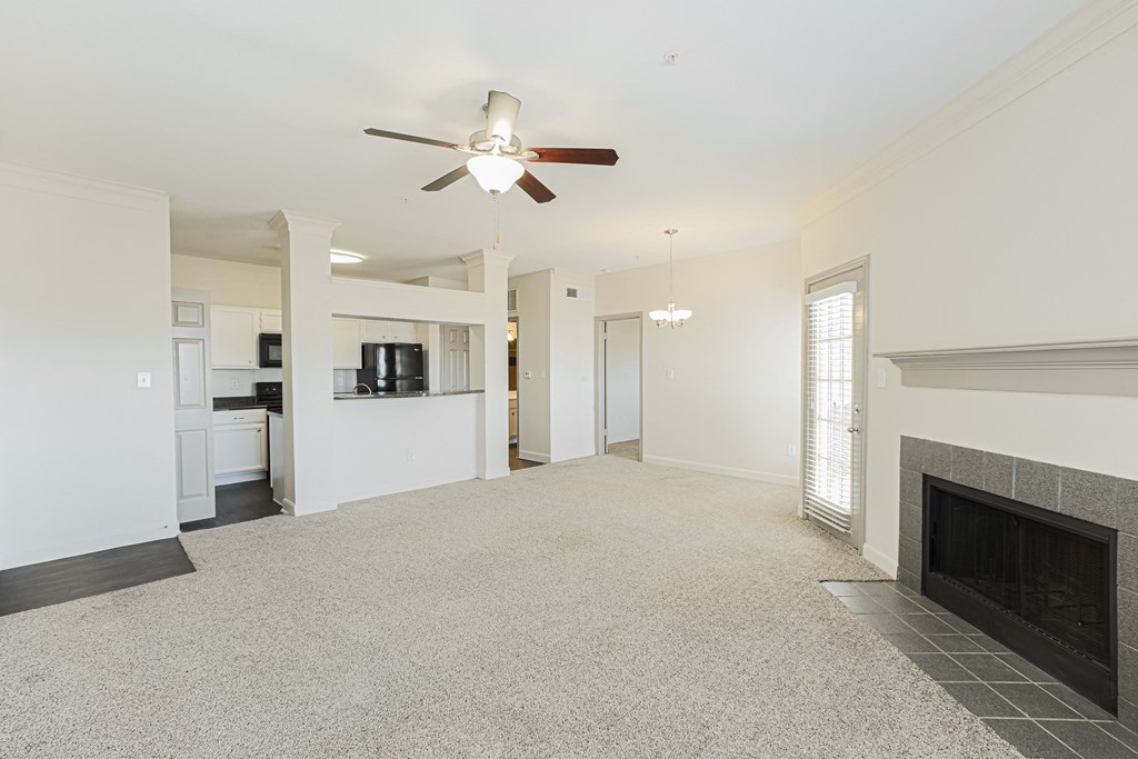 an empty living room with a ceiling fan and a fireplace