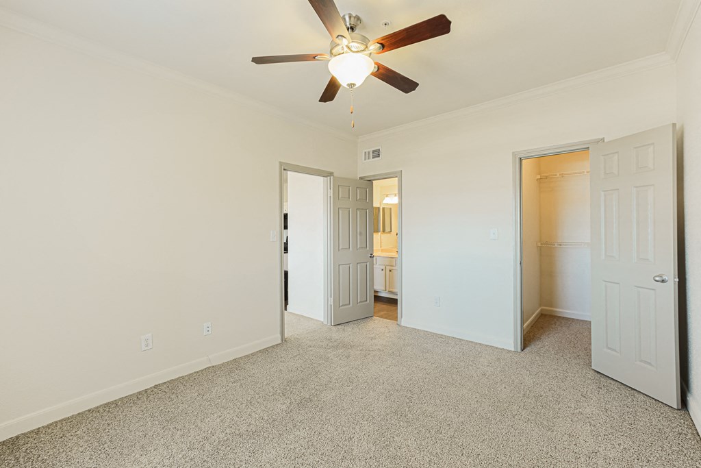 an empty living room with a ceiling fan and a door to a bathroom