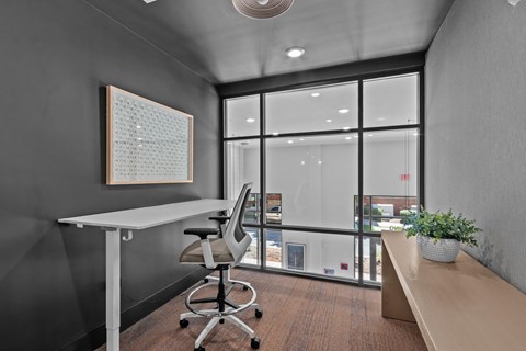 A modern office space with a desk, chair, and a view of the outside.