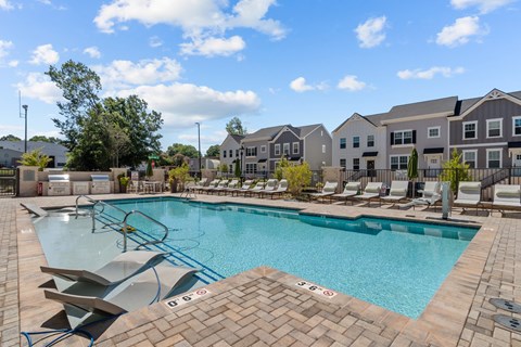A swimming pool surrounded by lounge chairs and apartment buildings.