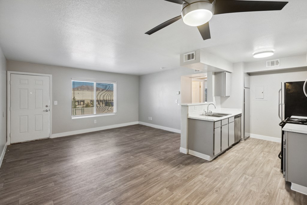 an empty living room and kitchen with a ceiling fan