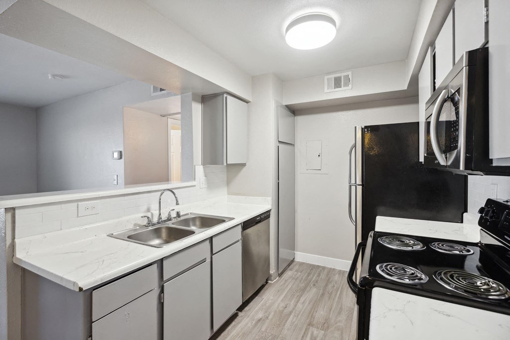 a kitchen with white cabinets and black appliances and a sink