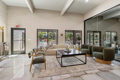 A modern living room with a glass coffee table and a view of the backyard.
