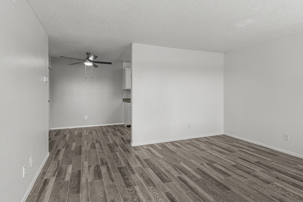 an empty living room with wood flooring and a ceiling fan