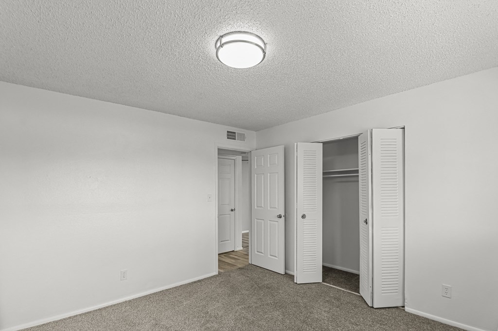 an empty bedroom with a closet and a mirrored closet door