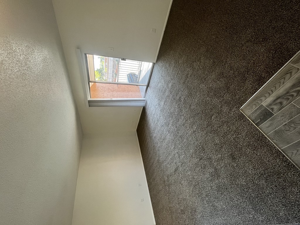 a view down a hallway with a window and a stair case