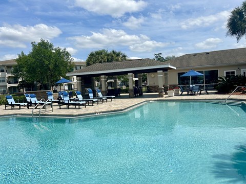 A swimming pool with sun loungers and a building in the background.