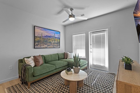 A living room with a green couch and a painting on the wall.