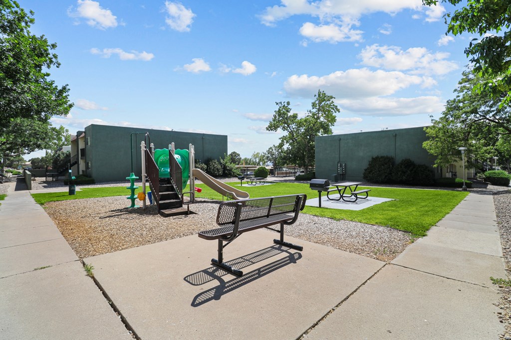a park with a playground and benches in front of a building