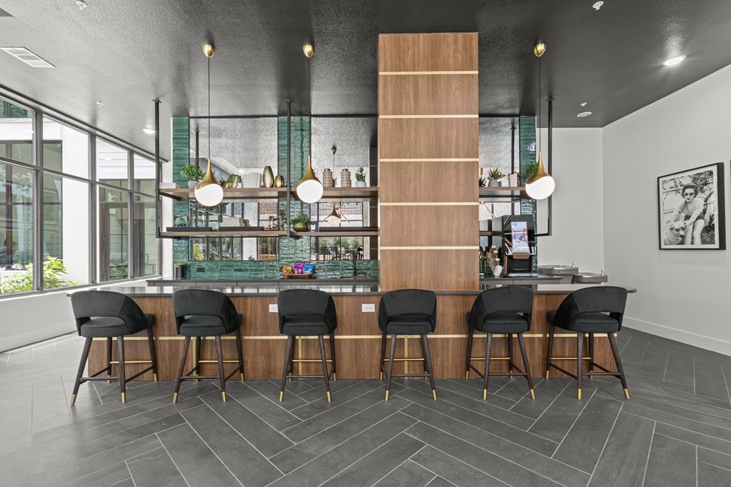 A modern bar with black chairs and a wooden counter.