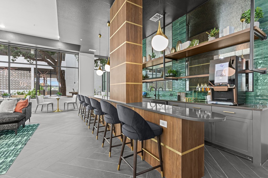 A modern bar area with a long wooden bar and black bar stools.