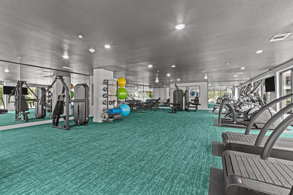A gym with a variety of equipment including treadmills, weights, and exercise machines.