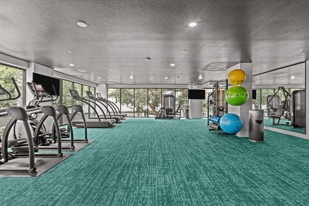 A gym with a green carpet and various exercise equipment.