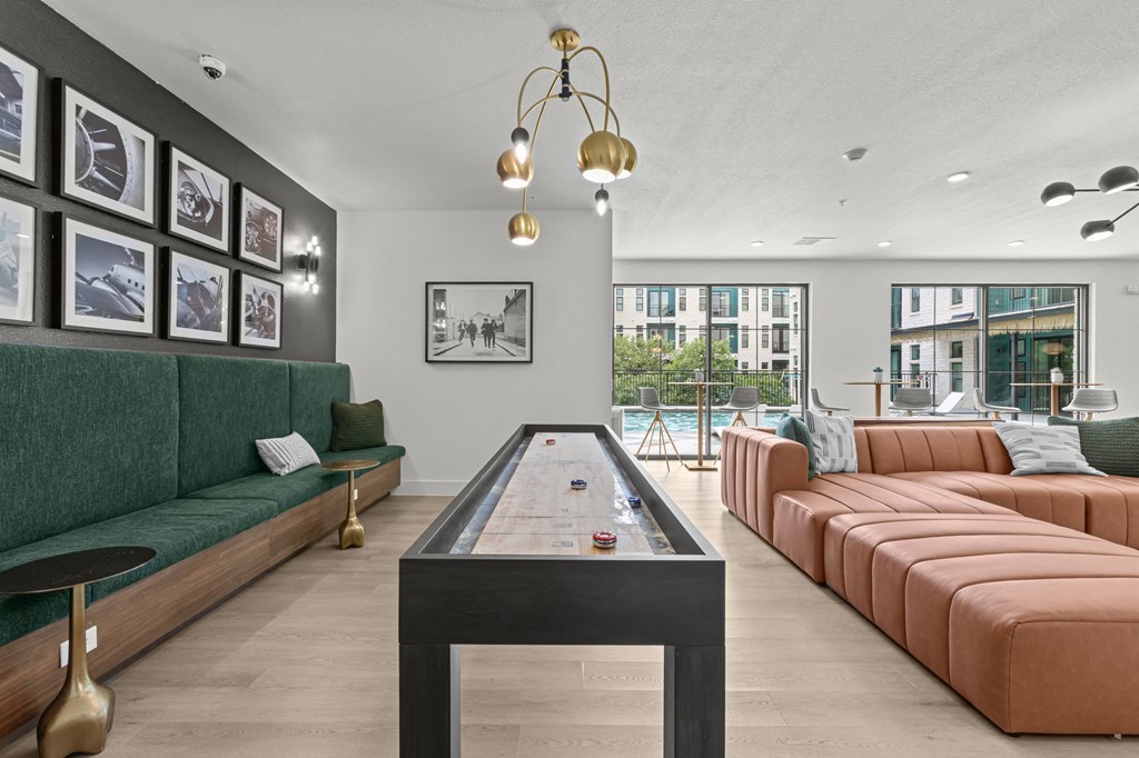 A billiard table is in the middle of a room with a green sofa and a brown sofa.