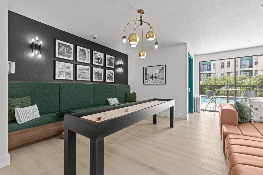 A billiard table is in the middle of a room with a green couch and pictures on the wall.