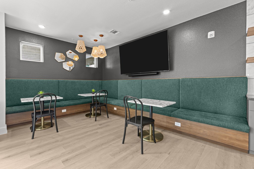 A room with a green couch and a television on the wall.