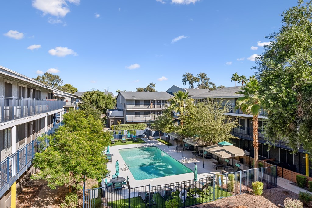A pool surrounded by trees and apartment buildings.