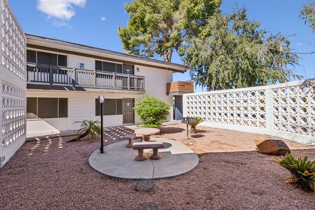 A patio area with a table and chairs in front of a building.
