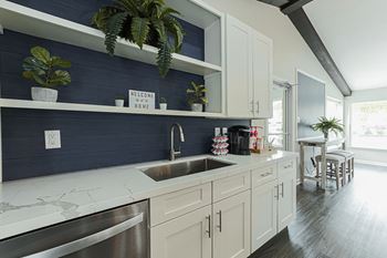 A kitchen with a white counter top and a stainless steel dishwasher.