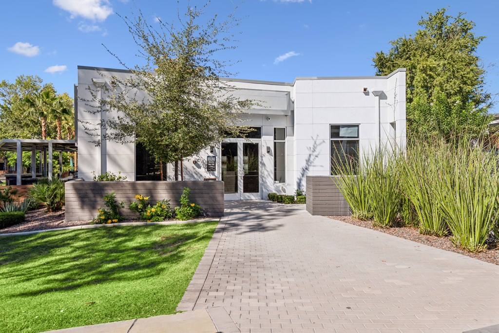 A white building with a grey roof and a black gate.