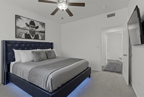 A bedroom with a large bed and a ceiling fan.