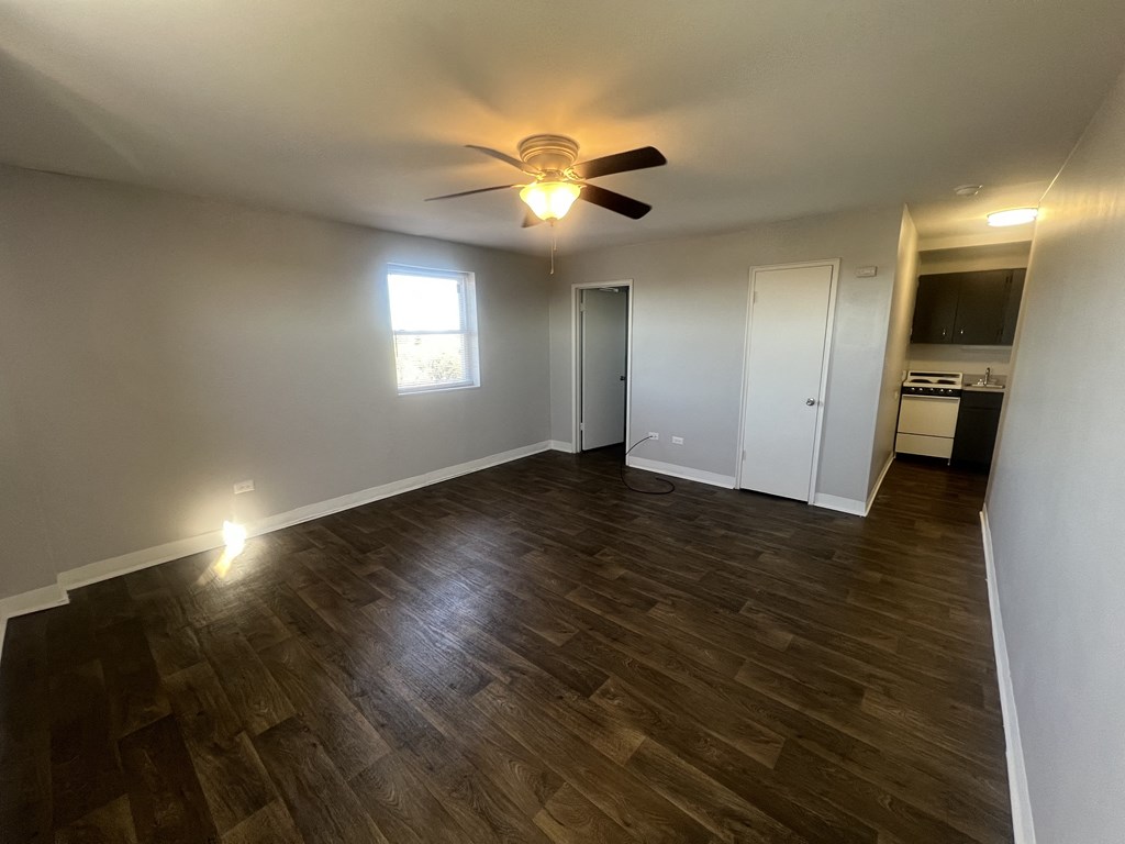 an empty living room with wood floors and a ceiling fan