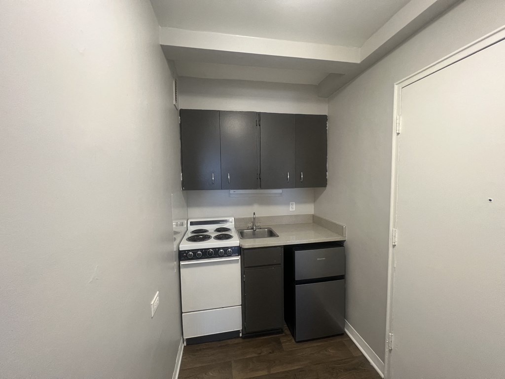 an empty kitchen with white appliances and black cabinets