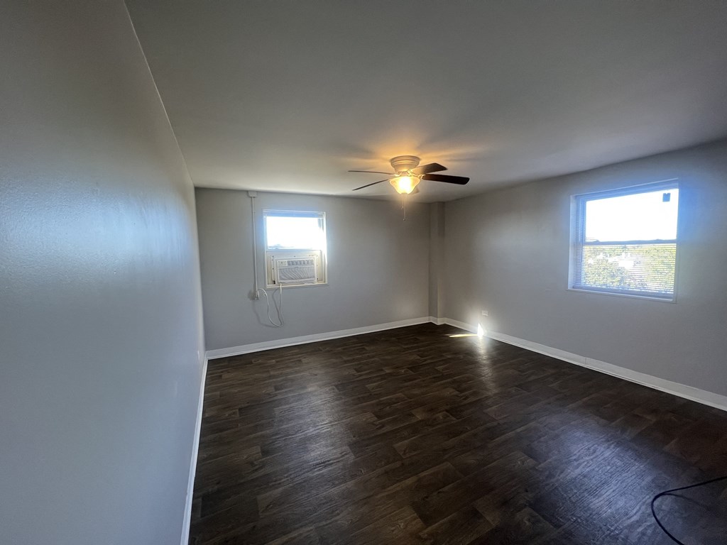 an empty living room with a ceiling fan and a window