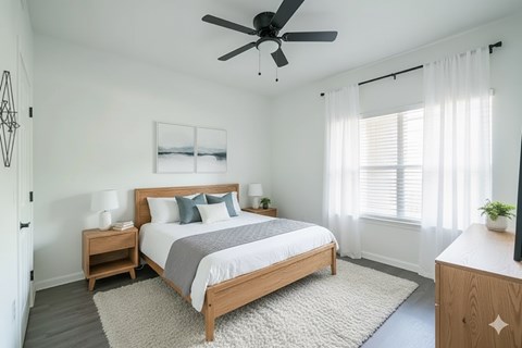 A bedroom with a large bed, a ceiling fan, and a window with white curtains.