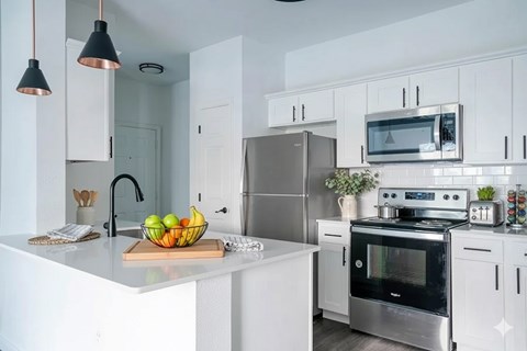 A kitchen with a white countertop and a bowl of fruit on it.