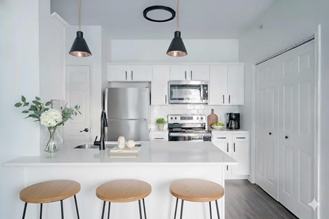 A modern kitchen with white cabinets and a stainless steel refrigerator.