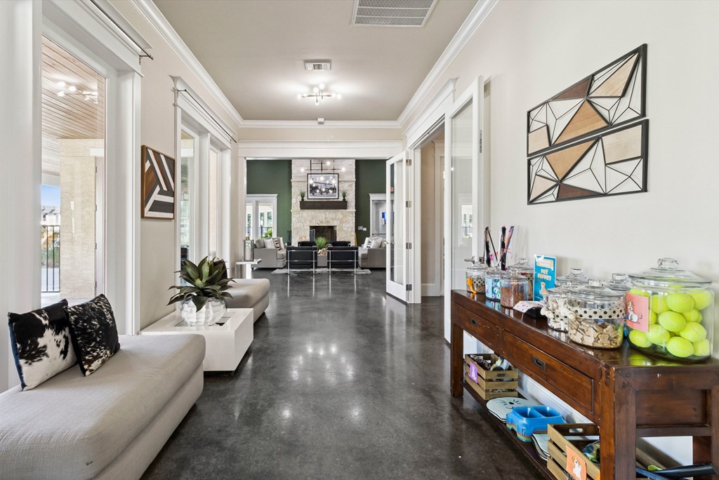 A long hallway with a white sofa and a wooden table with many items on it.