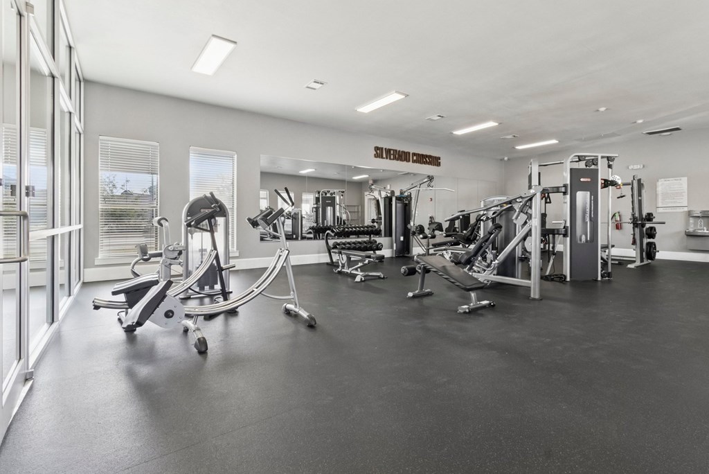 A gym with a variety of equipment including a treadmill, a stationary bike, and a rowing machine.